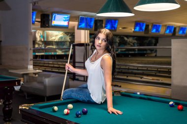 Bilardo masasının yanında esmer bir kadın.