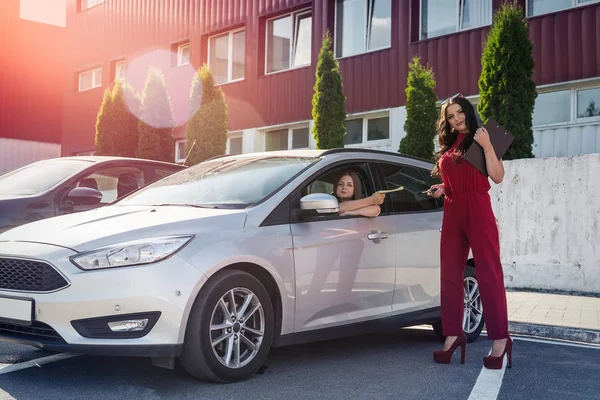 Kadın sürücü ve menajer dolar ve araba anahtarlarıyla değiş tokuş yapıyor.