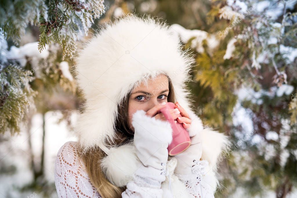 Young woman with cup of coffee in winter park