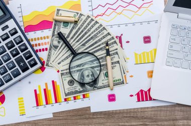 İş kavramı - grafik, büyüteç, dolar, hesap makinesi ve dizüstü bilgisayar