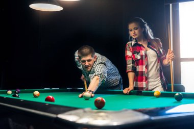 Bilardo oynayan arkadaşlar, topa vuran bir adam.