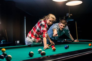 Bilardo oynayan çift, topa vuran adam.