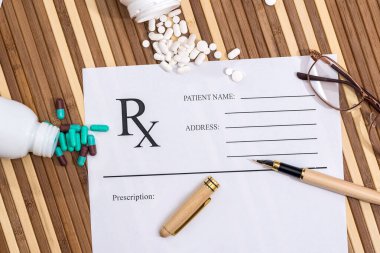 Dağınık haplar, bardaklar ve kalemle dolu boş reçete