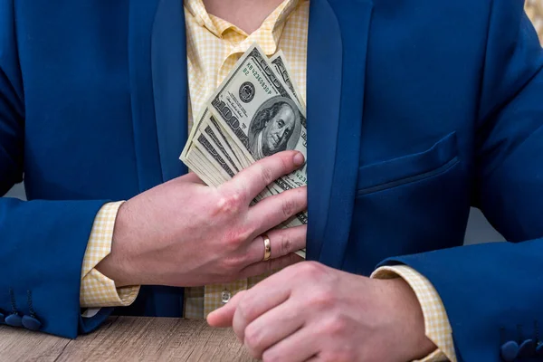 Business person hiding dollar notes into pocket
