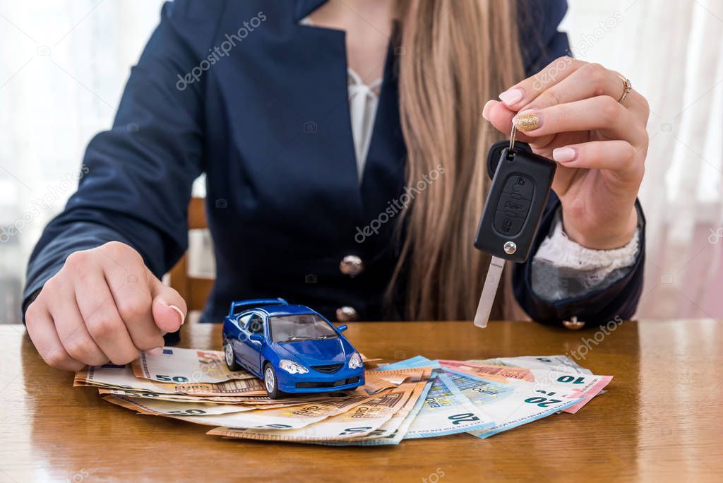 Dealer holding keys from car, toy car and euro money
