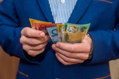 Avustralya Doları banknotlarını tutan erkek eller, yakın plan.