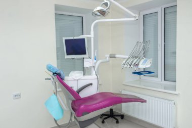 Hasta sandalyesinde aletler ve ekipmanlarla dişçilik yapıyor.