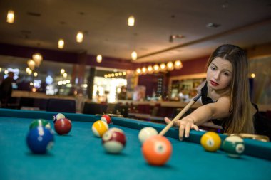 Young and beautiful woman in pub playing billiard