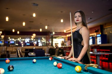 Young and beautiful woman in pub playing billiard