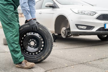 Worker hands with spare wheel, close up