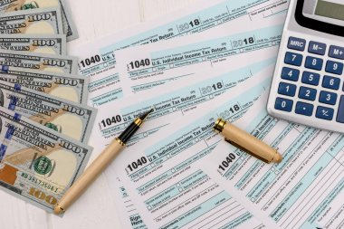 Dollars with pen, calculator and 1040 form