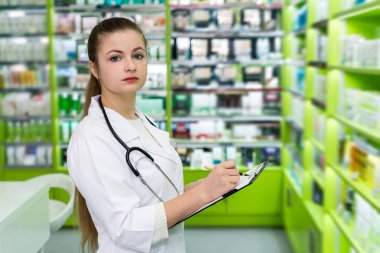 Eczanedeki ilaç listesini kontrol eden güzel bir eczacı.