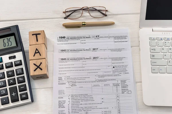 1040 formulário de imposto com dólar, laptop e cubos de madeira — Fotografia de Stock