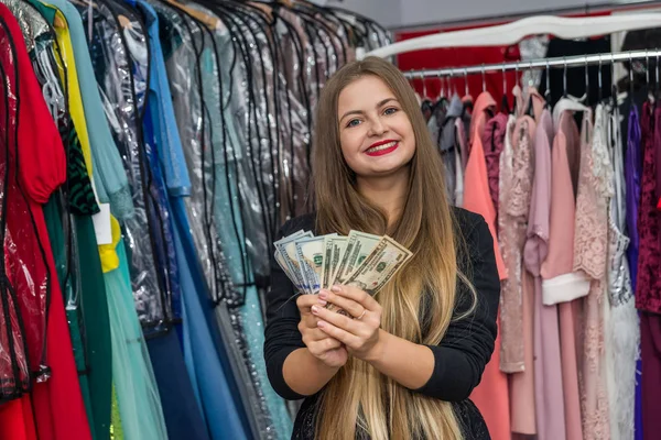 Счастливая женщина с долларами в магазине одежды — стоковое фото