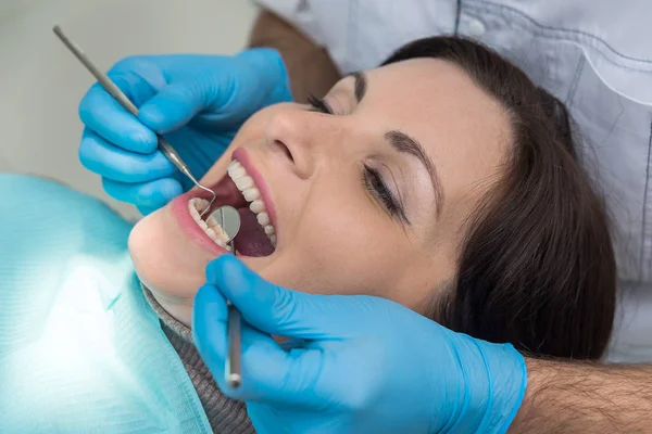Dentista checando os dentes da mulher com espelho durante a visita — Fotografia de Stock