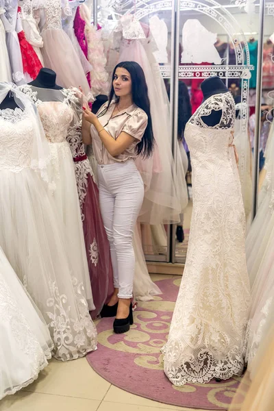 Seller in wedding salon demonstrating dresses for bride