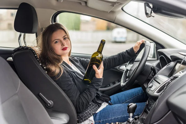 Mujer joven con botella conduciendo un coche — Foto de Stock