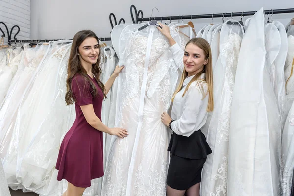 Молодые женщины в свадебном салоне выбирают платье — стоковое фото