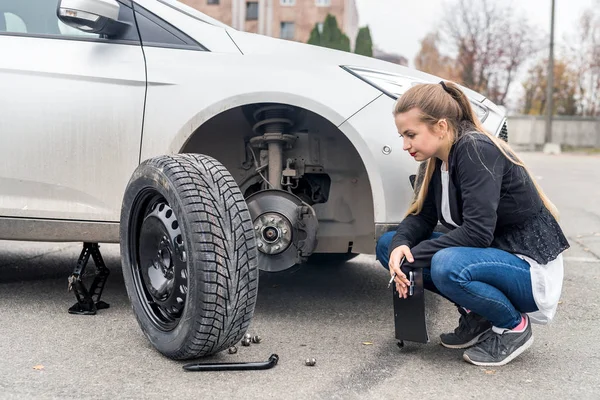 Žena v zoufalství při pohledu na náhradní kolo pro auto — Stock fotografie