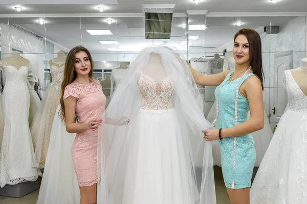 Costurera o consultor de bodas ayudar a la novia en el salón —  Fotos de Stock