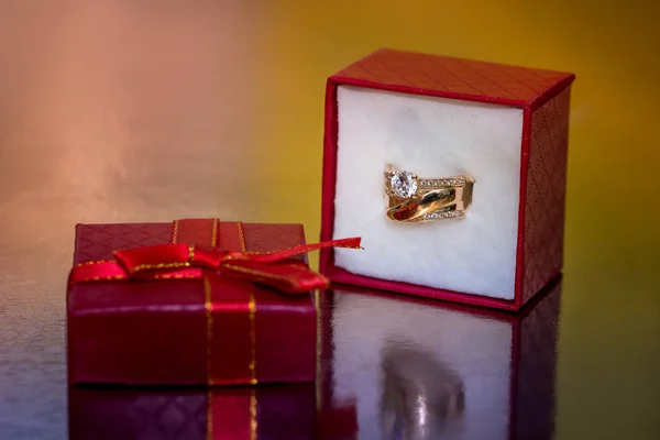 Golden ring in red gift box on golden background ストック画像