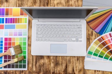 Ev tadilatı için ahşap masa üzerinde renk örnekleri olan dizüstü bilgisayar