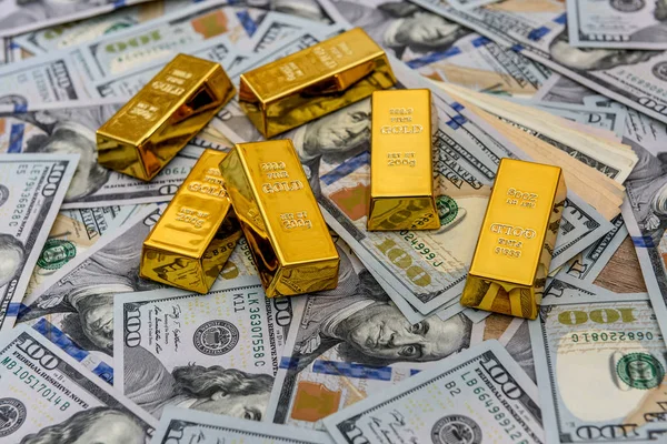 Zlaté cihly se stodolarovými bankovkami jako pozadí — Stock fotografie