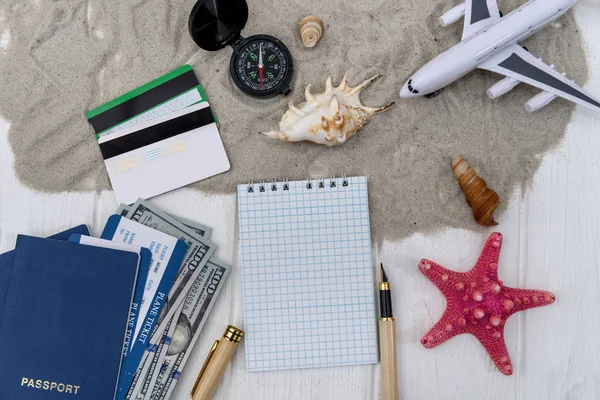 ノートパッドと砂の上のおもちゃの飛行機で旅行計画 — ストック写真