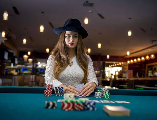 Kvinna i hatt med spelkort och pokermarker i casino — Stockfoto