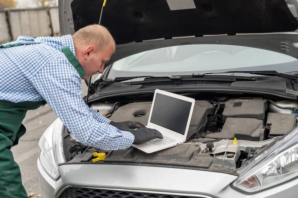 Mechanic making diagnostic of a car with laptop