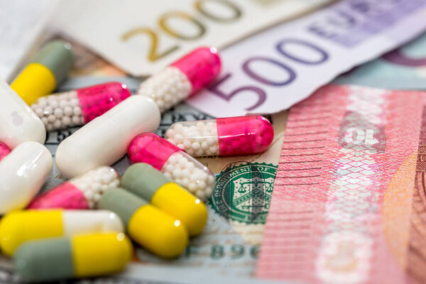 different pills on euro and dollar bills. medical concept.