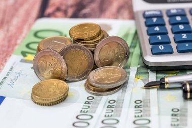100 Euro faturaları tükenmez kalem, sikke ve hesap makinesi.