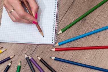 Ahşap masa üzerinde renkli kalemler ile boş kayda göre çizim kız