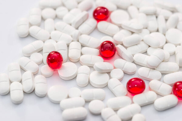 Много белых и красных таблеток на белом фоне
