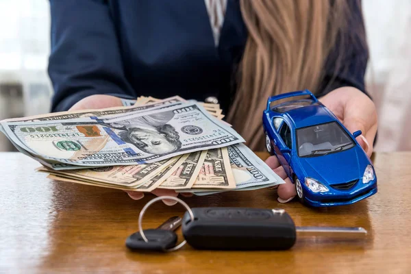 Female hands with dollars, car and keys