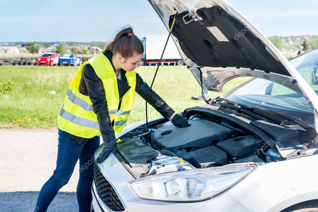 Beautiful woman checking car engine on roadside