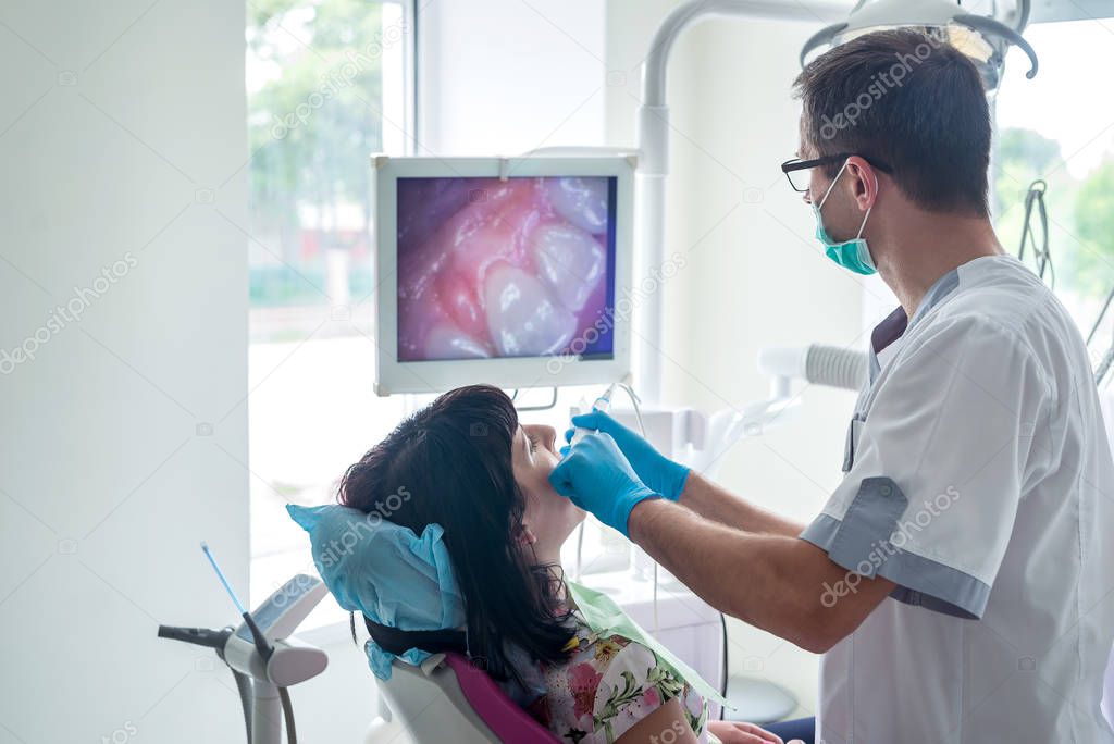 Dentist examining patient teeth with intraoral camera