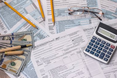 Tax form with dollar, calculator and pen