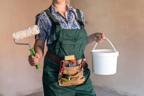 Female body in uniform with tool belt and painting equipment