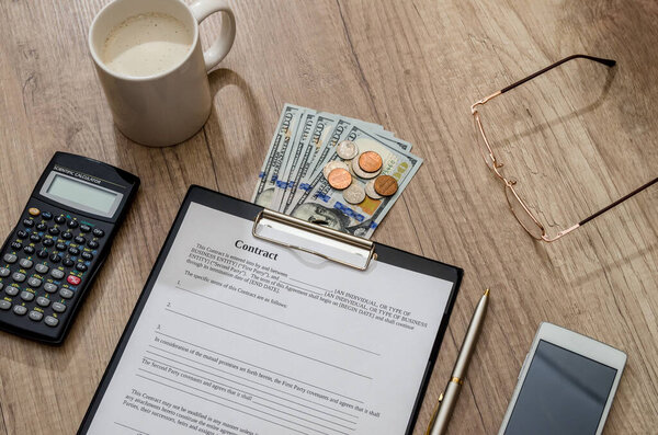 кофе и контракт, деньги, мобильный телефон на столе
