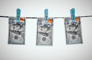 Beyaz sırtta izole edilmiş halatla 100 dolar kurutuluyor.