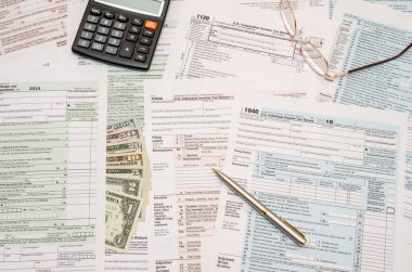 1040 vergi formu, kalem, dolar ve hesap makinesi