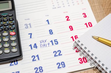 Calculator and pen on paper calendar