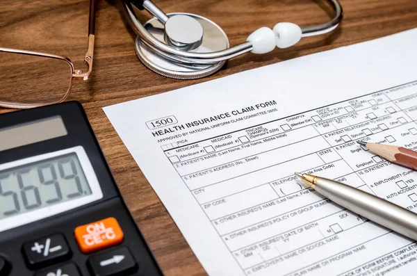 health insurance claim form with stethoscope on clipboard, syringe, calculator and pen