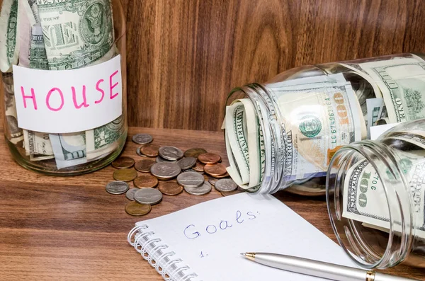 finance idea - new years resolutions with dollar in glass jar, coins on wooden table