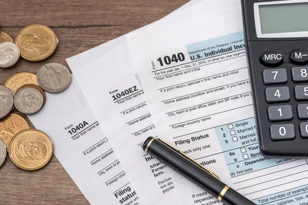 1040 tax form, us coins, pen and calculator