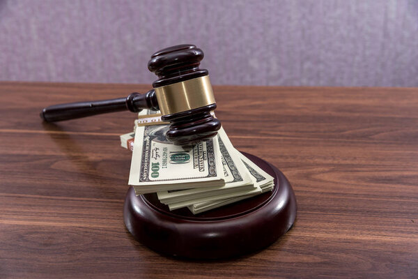 Judge gavel with dollars on wooden table