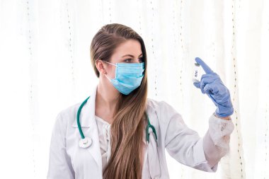 Genç, güzel doktor ampuldeki aşıya bakıyor.