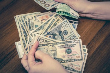 Avro ve dolar banknotlarını ahşap masanın üzerinde tutan kadın.