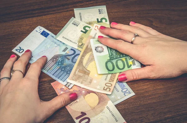 Жінка тримає євро банкноти над дерев'яним столом — стокове фото